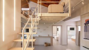 A modern interior with a wooden staircase, a loft bedroom with a cushioned bed, and a bathroom with a bathtub.