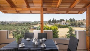 A covered outdoor seating area with a table set for tea, overlooking a scenic landscape.