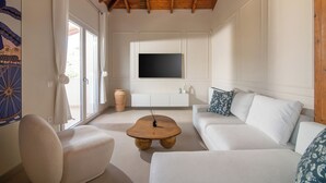 A modern living room with a wooden ceiling, a white sofa, a coffee table, and a TV mounted on the wall.