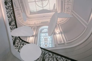Stunning staircase with ornate railings leads to a grand upper level featuring a beautiful stained glass window.
