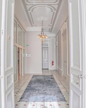 Classic hallway with a chandelier, patterned rug, and elegant wallpaper.
