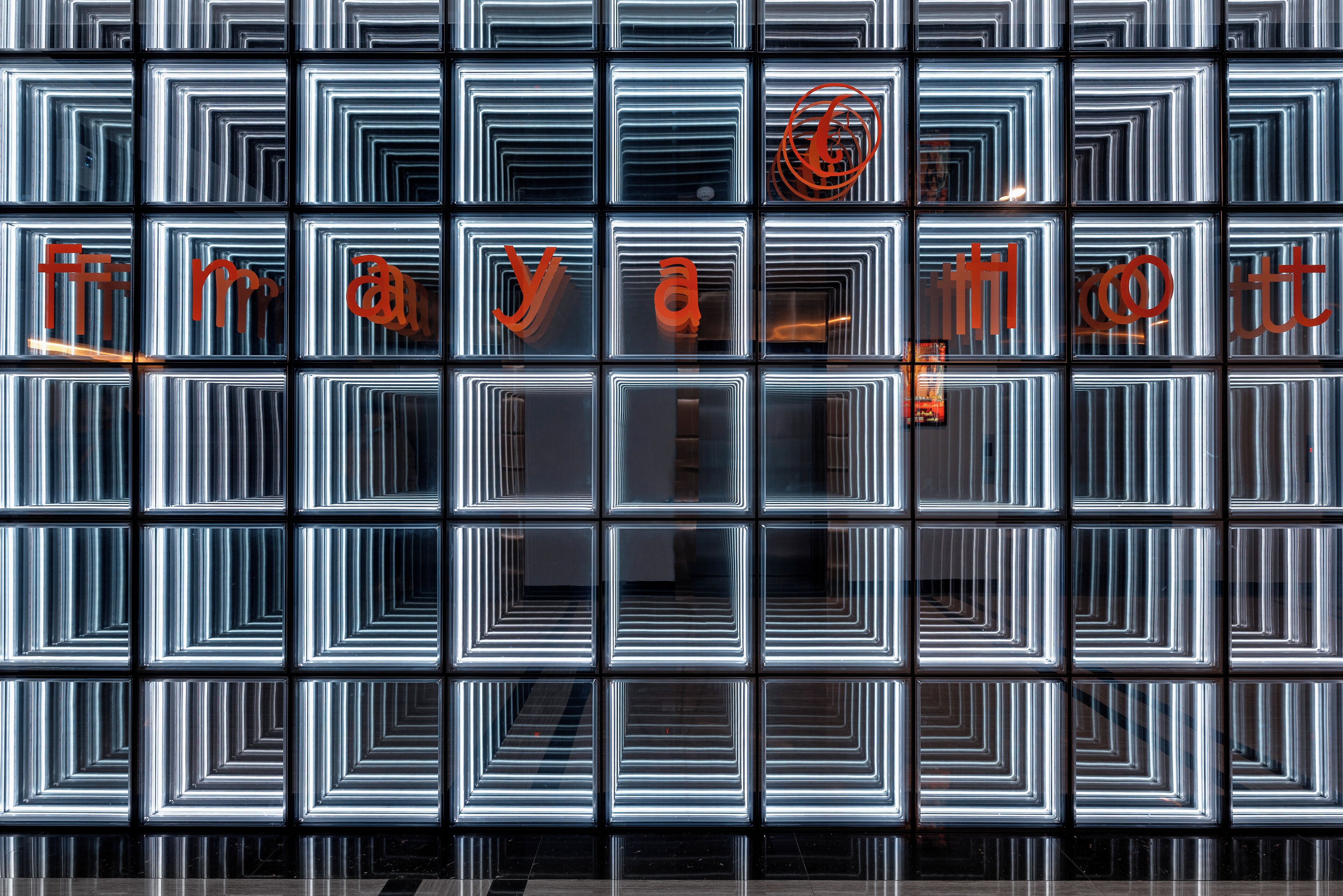 A wall with a geometric pattern and illuminated text.