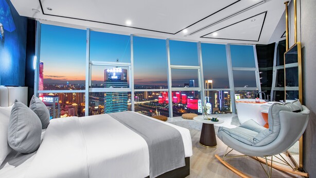 A modern hotel room with a large bed, a seating area, and a city view. - Fraya High - altitude Future Hotel (Chongqing)
