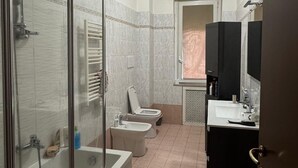 Een badkamer met een douche met glazen wand, een toilet, een bidet en een wastafel.