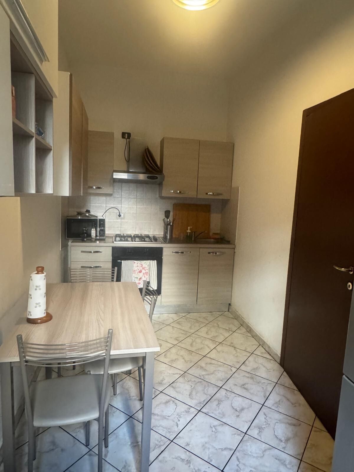 Une cuisine de taille réduite comprenant une table et des chaises, un fourneau et des placards.