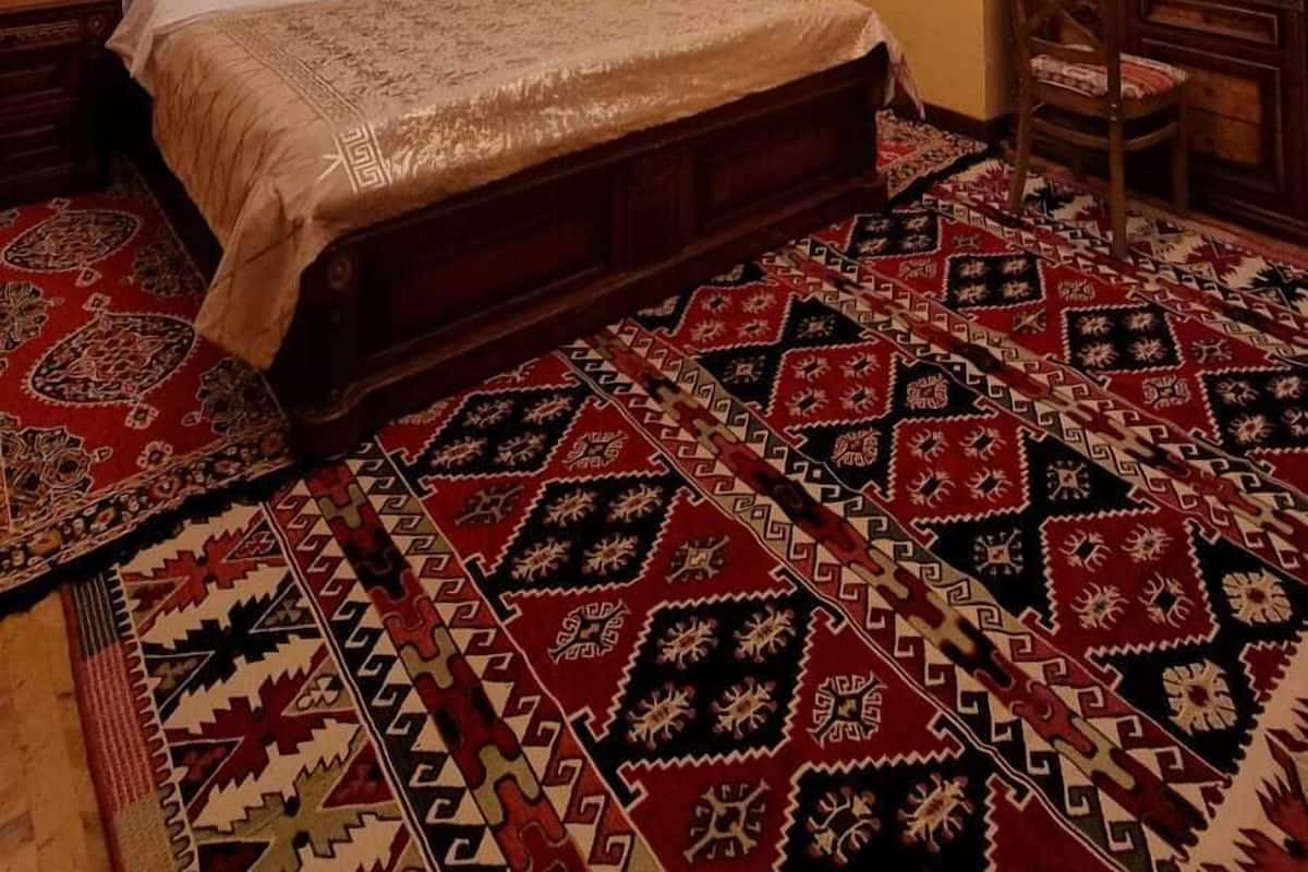 Une pièce avec un lit en bois, une moquette à motifs, un lustre et des murs en briques.
