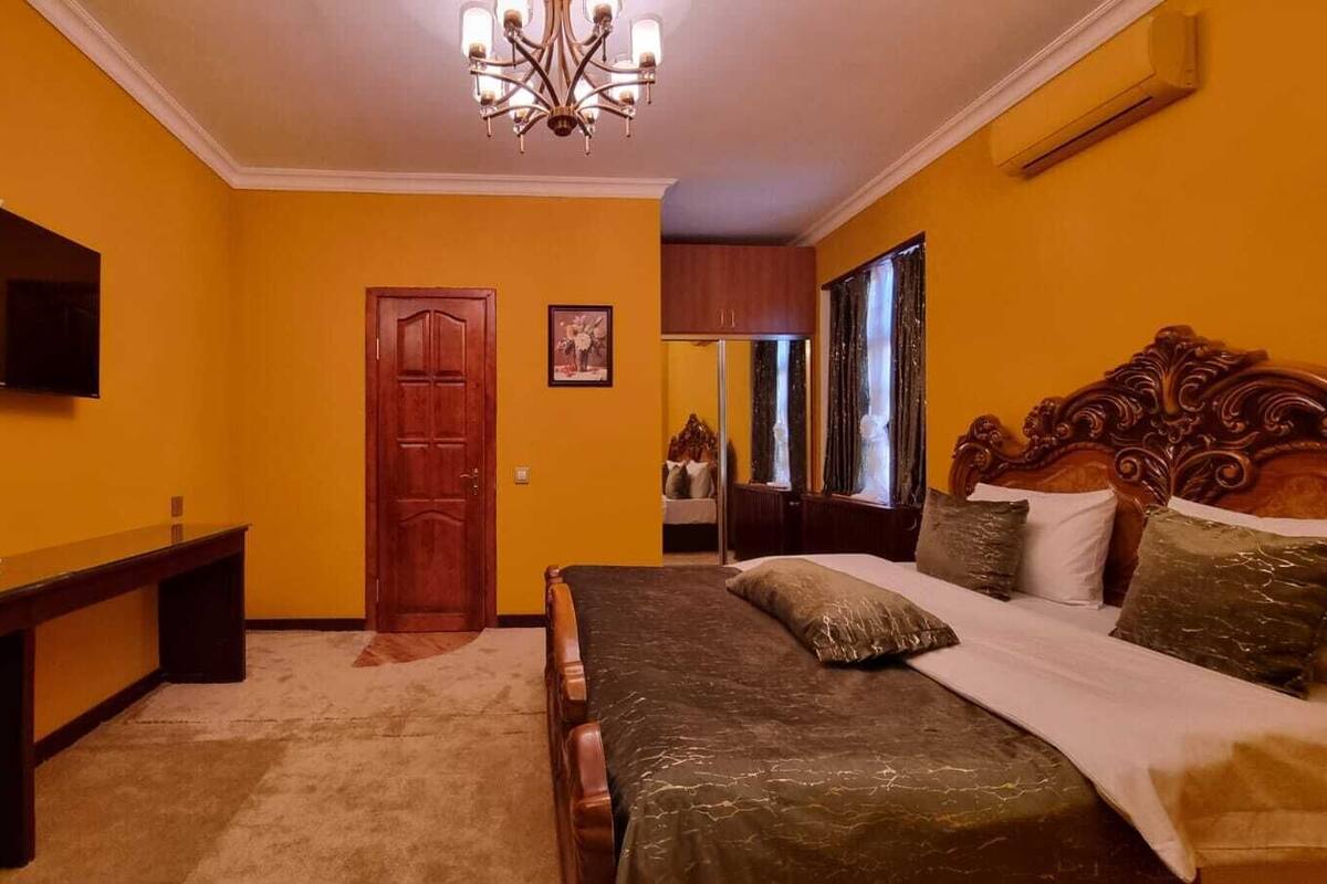 Une chambre à coucher avec un lit, un bureau, une chaise, un téléviseur et une porte.