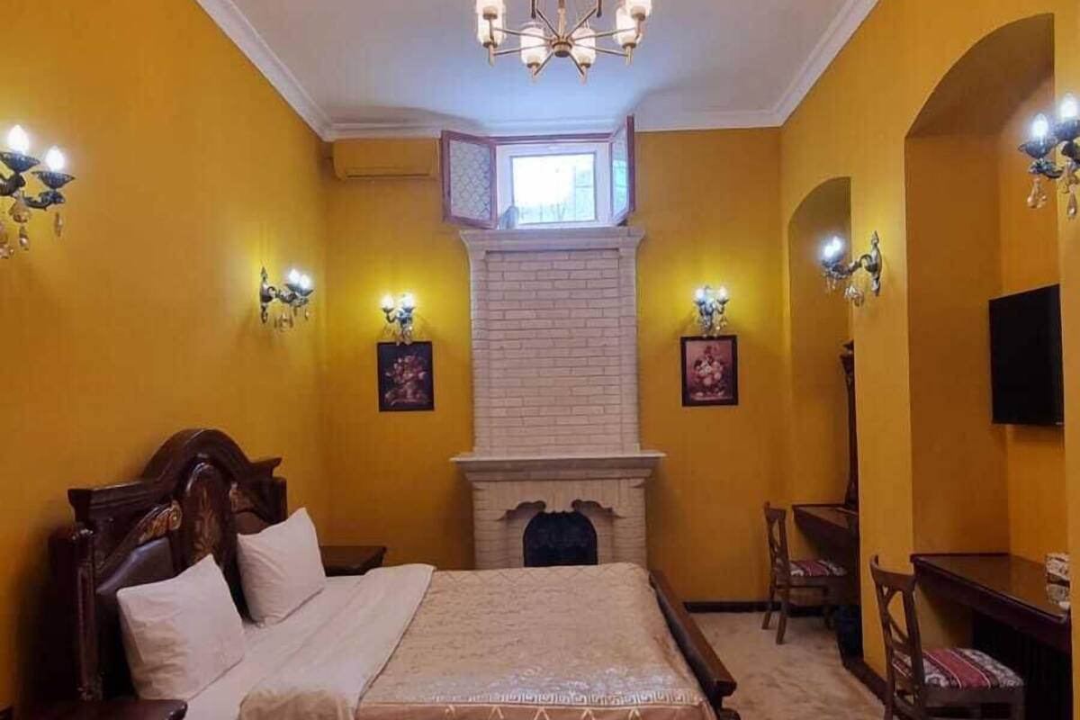 Une chambre à coucher avec un grand lit, une cheminée, un lustre et un bureau avec une chaise.