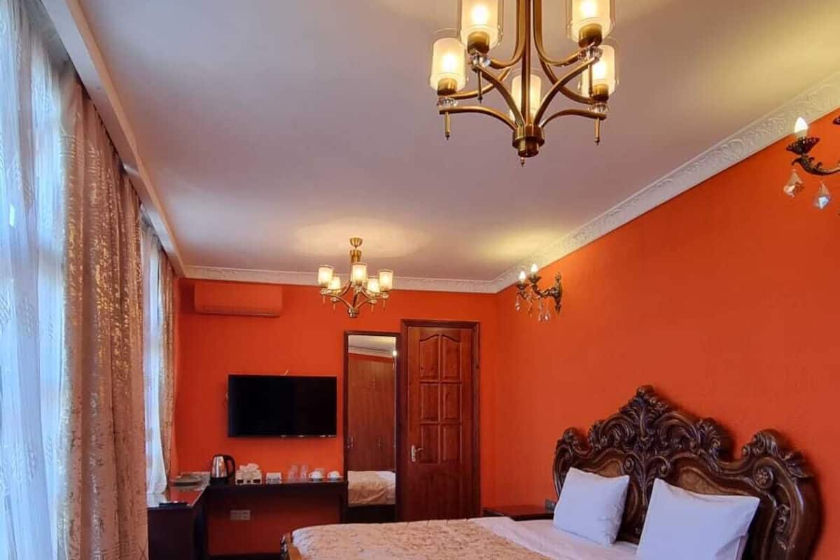 Une chambre à coucher avec un grand lit, un lustre, une télévision et une armoire.