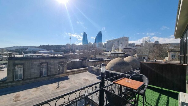 A rooftop terrace with a view of a cityscape, including modern buildings and a tower. - Boutique Hotel Grandview (Baku)