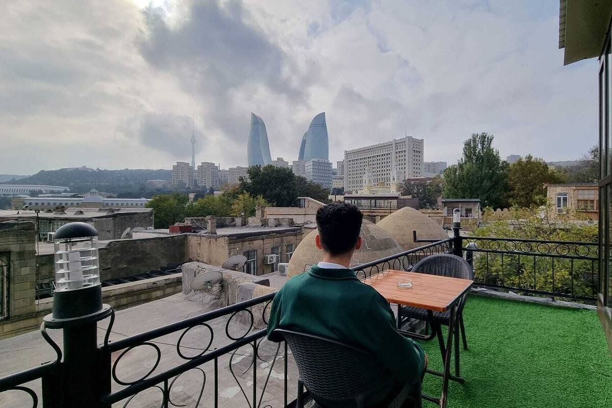 Un balcon avec une table et des chaises, donnant sur un paysage urbain composé d’immeubles modernes et d’une tour.