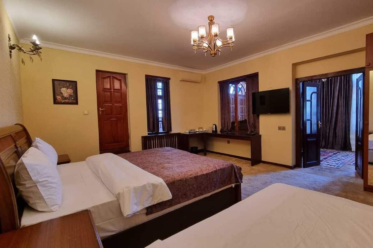 Une chambre d’hôtel avec deux lits, un bureau, une télévision et un lustre.