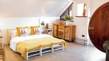 A bedroom with a bed, wooden dresser, and a large wooden door.