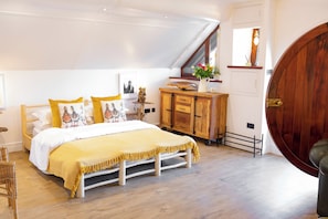 A bedroom with a bed, wooden dresser, and a large wooden door.