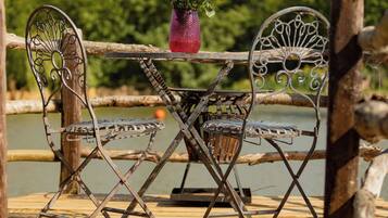 Une terrasse en bois avec des chaises et une table en métal, donnant sur une étendue d’eau.