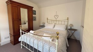 Un dormitorio con cama con dosel, un armario de madera, un espejo, dos mesitas de noche y una decoración con forma de corazón en la pared.
