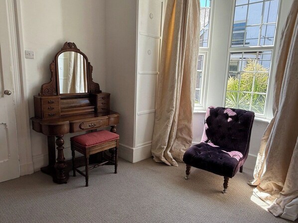 Una habitación con un aparador de madera, una silla tapizada en rojo y un sillón de terciopelo.