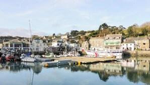 A harbor with boats docked, buildings, and a calm water surface reflecting the surroundings. - Lodge 9 - Lamorna (Padstow)