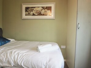 Una habitación de hotel con una cama, un cuadro de flores en la pared y una puerta con pomo.