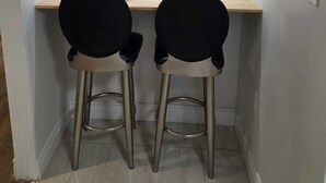 Et lille, lukket rum med to sorte stole og et træbord, udstyret med loftslamper.
