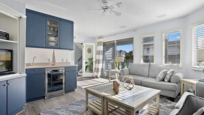 A modern kitchen with blue cabinets, a dining area with a wooden table, and a living room with a gray sofa. - Large 6 bedroom,7.5 bath house in Avalon, NJ-POOL  & Ocean Views- 3rd from beach (Avalon)