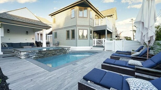 A backyard with a swimming pool, lounge chairs, and a stone feature. - Large 6 bedroom,7.5 bath house in Avalon, NJ-POOL  & Ocean Views- 3rd from beach (Avalon)