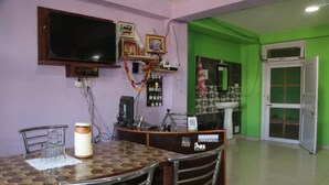 Una zona de recepció amb un taulell d'informació, un televisor penjat a la paret, un rellotge i una pared verd.