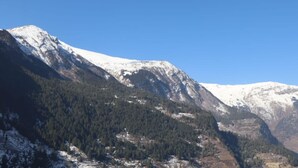 Paisatge montanyós amb cims nevats i zones boscoses denses.