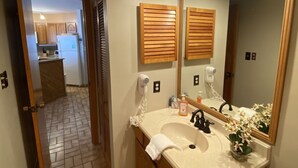 A bathroom with a large mirror, a sink, a towel, and a hairdryer.