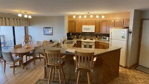 A compact kitchen with wooden cabinets, a central island, and a dining area with chairs.