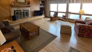 A spacious living room with a fireplace, a television, and comfortable seating including a sofa and armchairs.