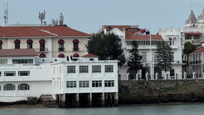 A waterfront building with multiple balconies and a red-tiled roof.