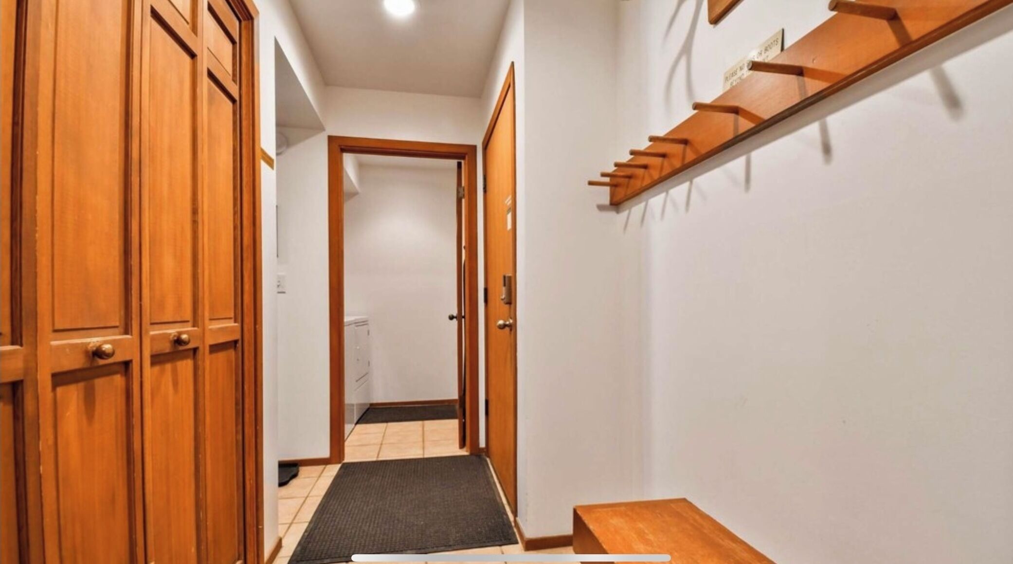 A hallway with wooden doors, a small table, and a shelf with hooks.