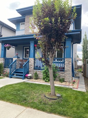 A two-story house with a stone facade, blue trim, and a front porch with steps. - Blue Kuti B&B (Edmonton)