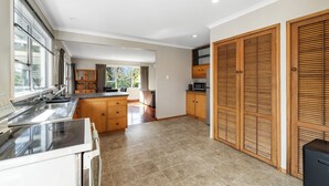 A modern kitchen with a large island, wooden cabinets, and a view of the outdoors.