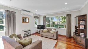 A spacious living room with two sofas, a flat-screen TV, and a wooden cabinet.