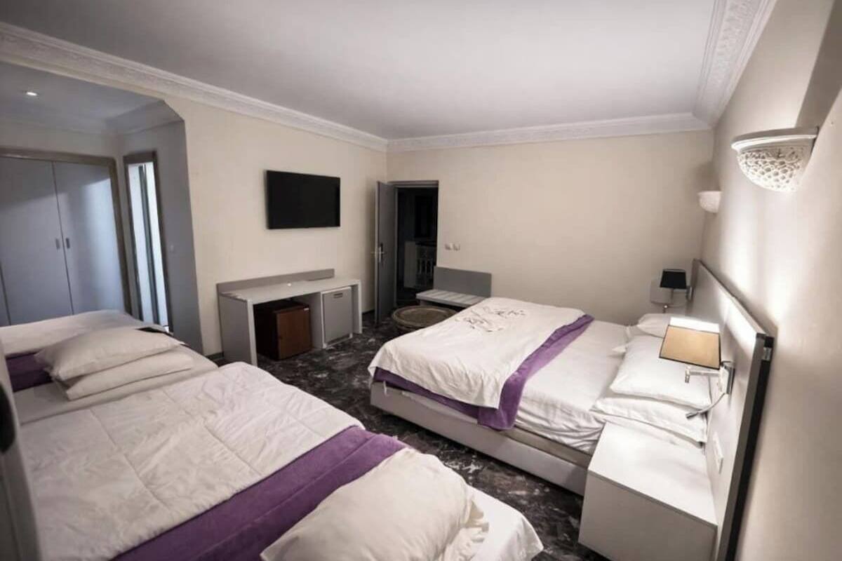 Habitación de hotel con dos camas, un escritorio, televisión y baño.