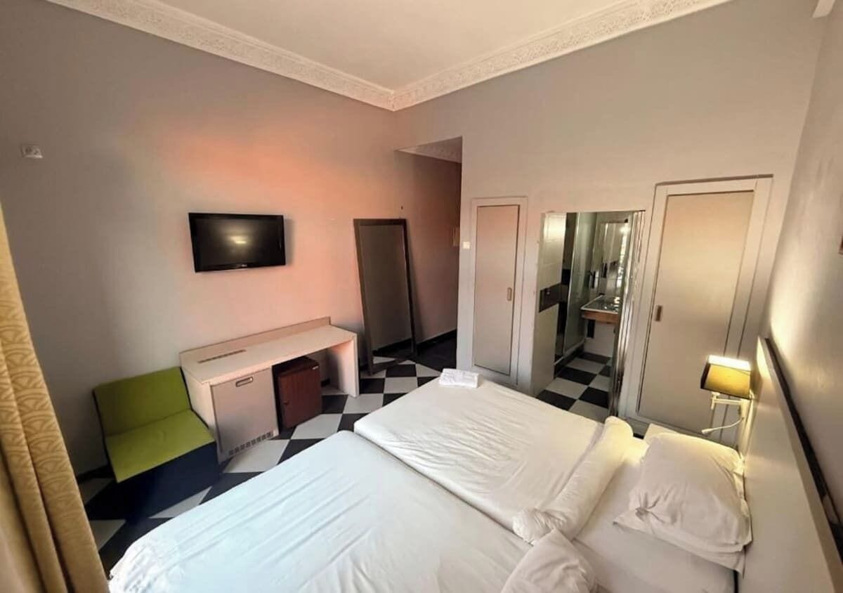 A hotel room with a bed, a desk, a television, and a mirror.