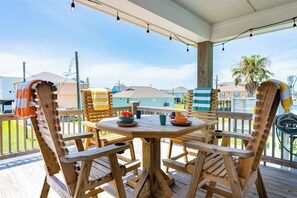 A wooden deck with a round table and chairs, surrounded by a railing.
