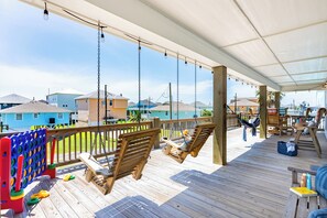 A wooden deck with swings, a pool table, and a view of houses.