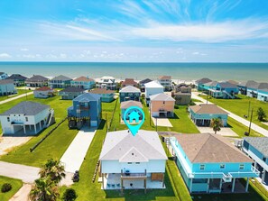 Vista aérea de una zona residencial costera con casas, una playa y un cielo despejado.