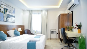 A hotel room with a large bed, a desk, a chair, and a potted plant. - Lavida luxe Apartments  (Riyadh)