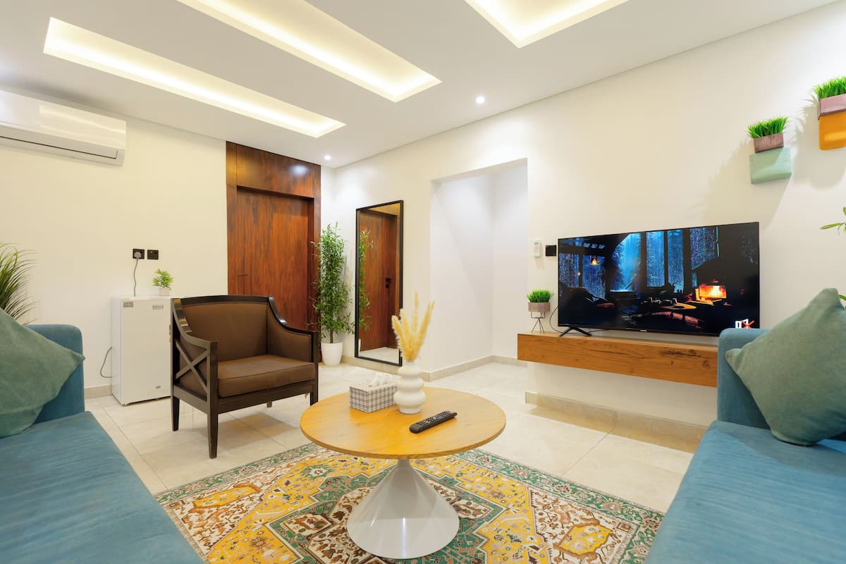A modern living room with a sofa, a coffee table, a TV, and a small refrigerator.