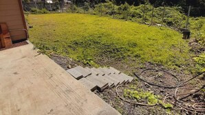 Een achtertuin met gazon, een tuinhuisje en een tuinslang.