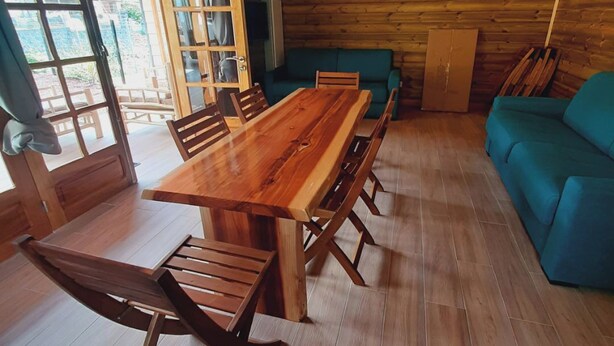 Een kamer met houten lambrisering, een grote eettafel, stoelen, een bank en een kast.