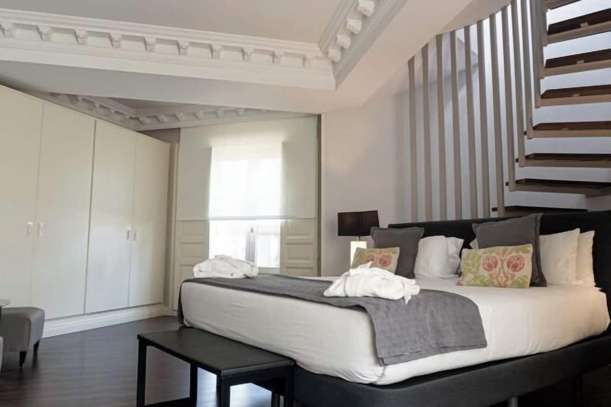 Une chambre à coucher avec un lit, des tables de chevet, une armoire et une fenêtre.