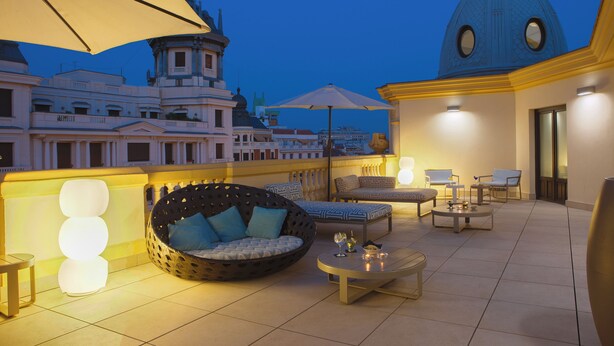 A rooftop terrace with outdoor seating, a large umbrella, and a view of a historic building with a dome. - Sardinero Madrid (Madrid)