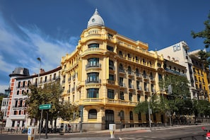 A historic yellow building with a dome, labeled 'HOTEL,' featuring ornate balconies and a corner entrance. - Sardinero Madrid (Madrid)