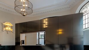 Een modern interieur met een groot donker paneelwand, een vloerkleed met een patroon en een kroonluchter.