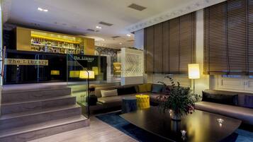 A modern living room with a sofa, coffee table, and a staircase leading to a bar area labeled "The Library Lounge".
